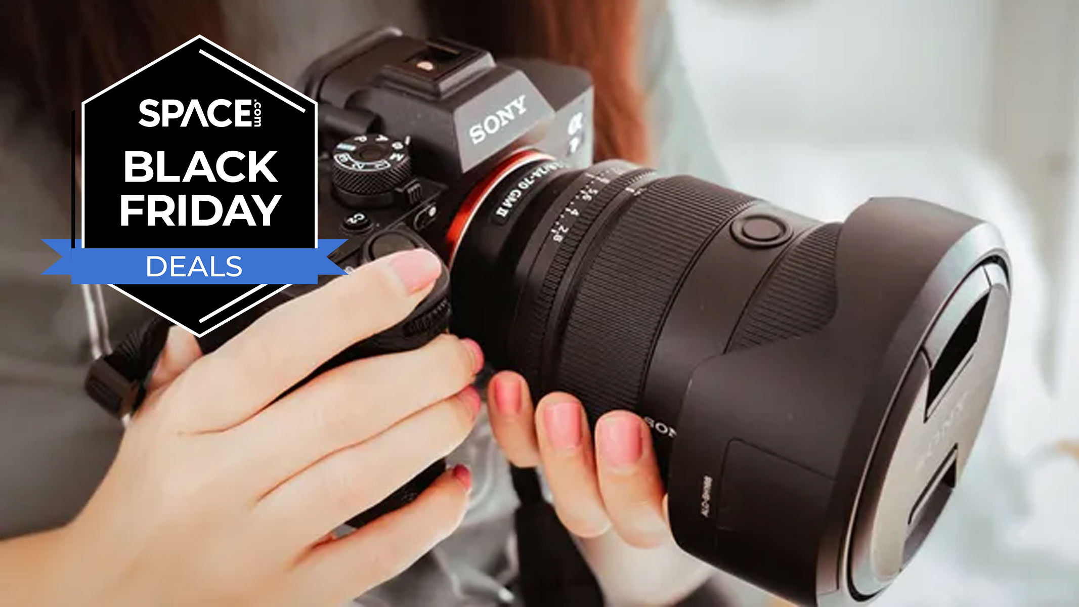 Hands holding a Sony camera and a Sony lens with a black Space.com Black Friday deals badge in the upper-left corner.