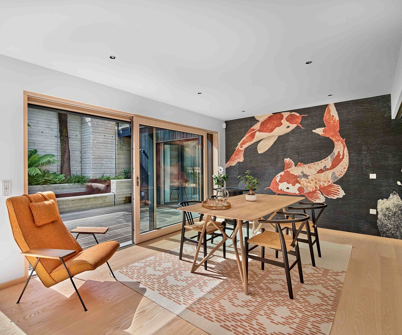 A Japanese-inspired open-plan living dining room, with large carp mural on the back wall. The space overlooks a courtyard