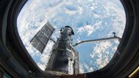 The Hubble Space Telescope is seen through one of the upper flight deck windows aboard space shuttle Atlantis during the STS-125 servicing mission in May 2009.
