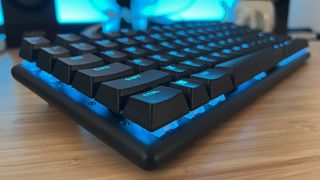 Corner of Alienware Pro Wireless gaming keyboard on a wooden desk