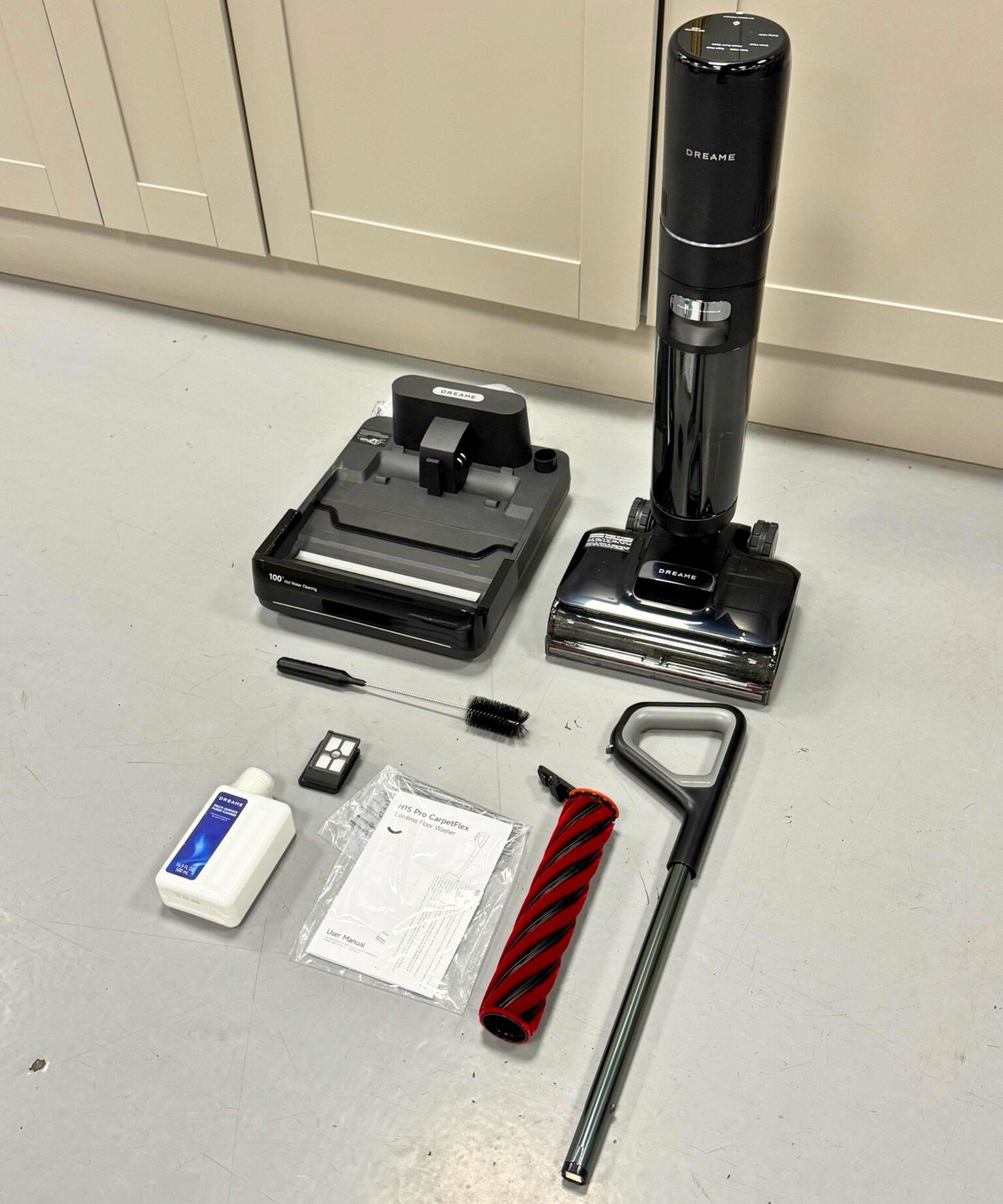 All parts for the Dreame H15 Pro CarpetFlex vacuum-mop combo on gray floor in front of cabinets.