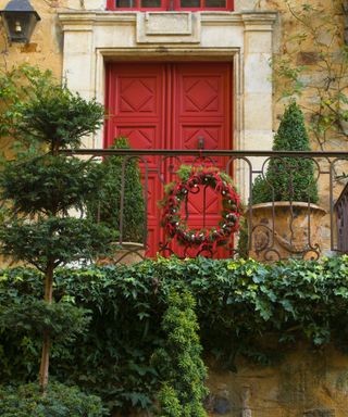 balcony christmas decor with topiary evergreens and a wreath