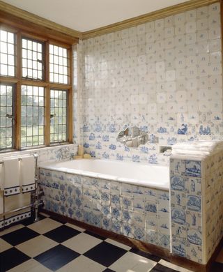 View of the Ireton Bathroom at Packwood House, showing the bath, window, towel rail and Dutch Delft tiles.