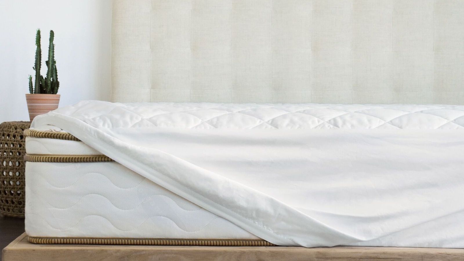 Saatva Waterproof Mattress Protector on a bed against a white wall. 