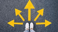 Top view of a person standing on asphalt with yellow arrows pointing in different direction