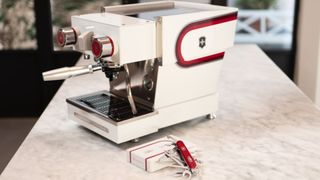 The Victorinox x La Marzocco Barista Tool lays next to an espresso machine