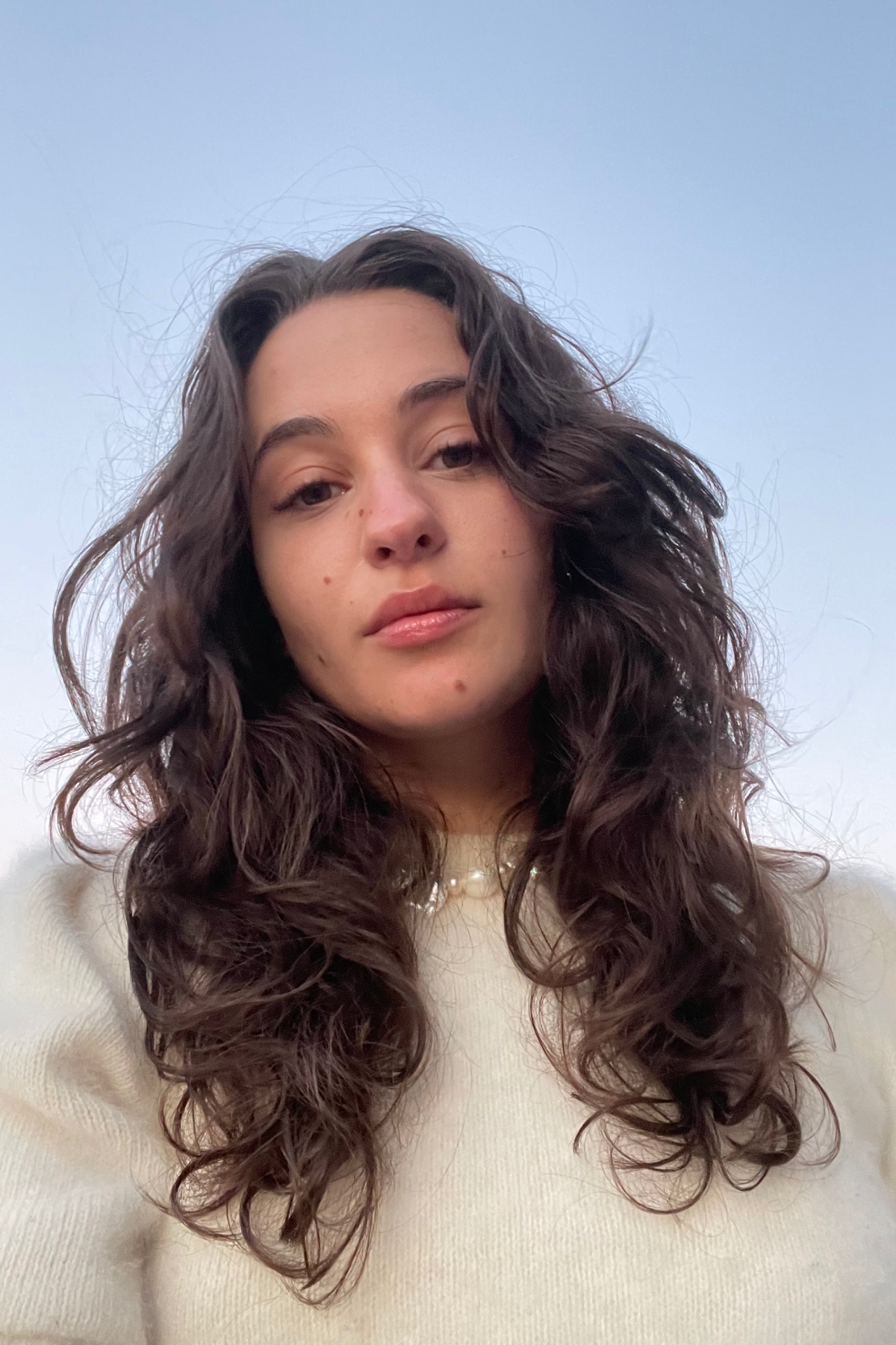a white woman with brown hair in a cream turtleneck