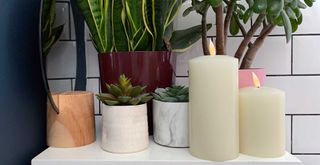 Flameless candles on a side table in a bathroom surrounded by plants