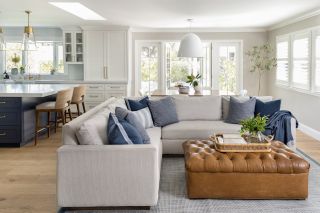 living room in open plan with kitchen, greige sofa and brown leather coffee table