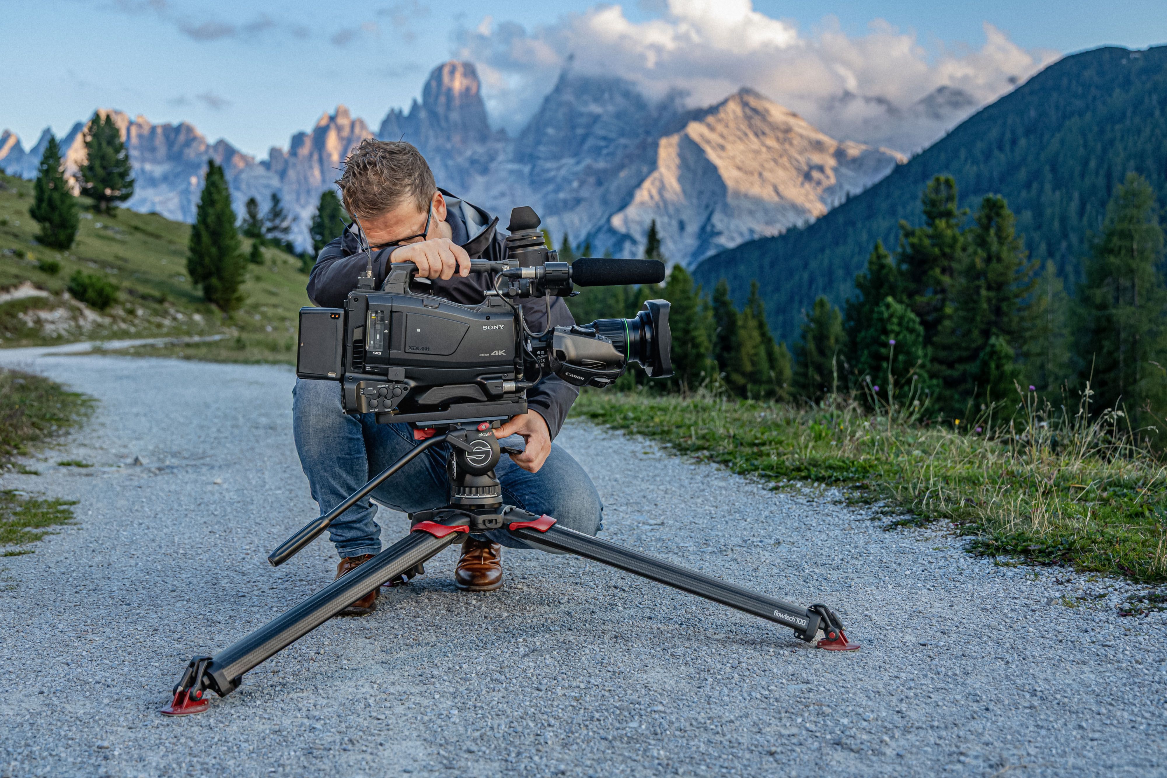 Sachtler head used by man on a trail with a mountain rage in the background. 