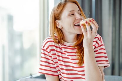 Woman craving sugar and eating a doughnut