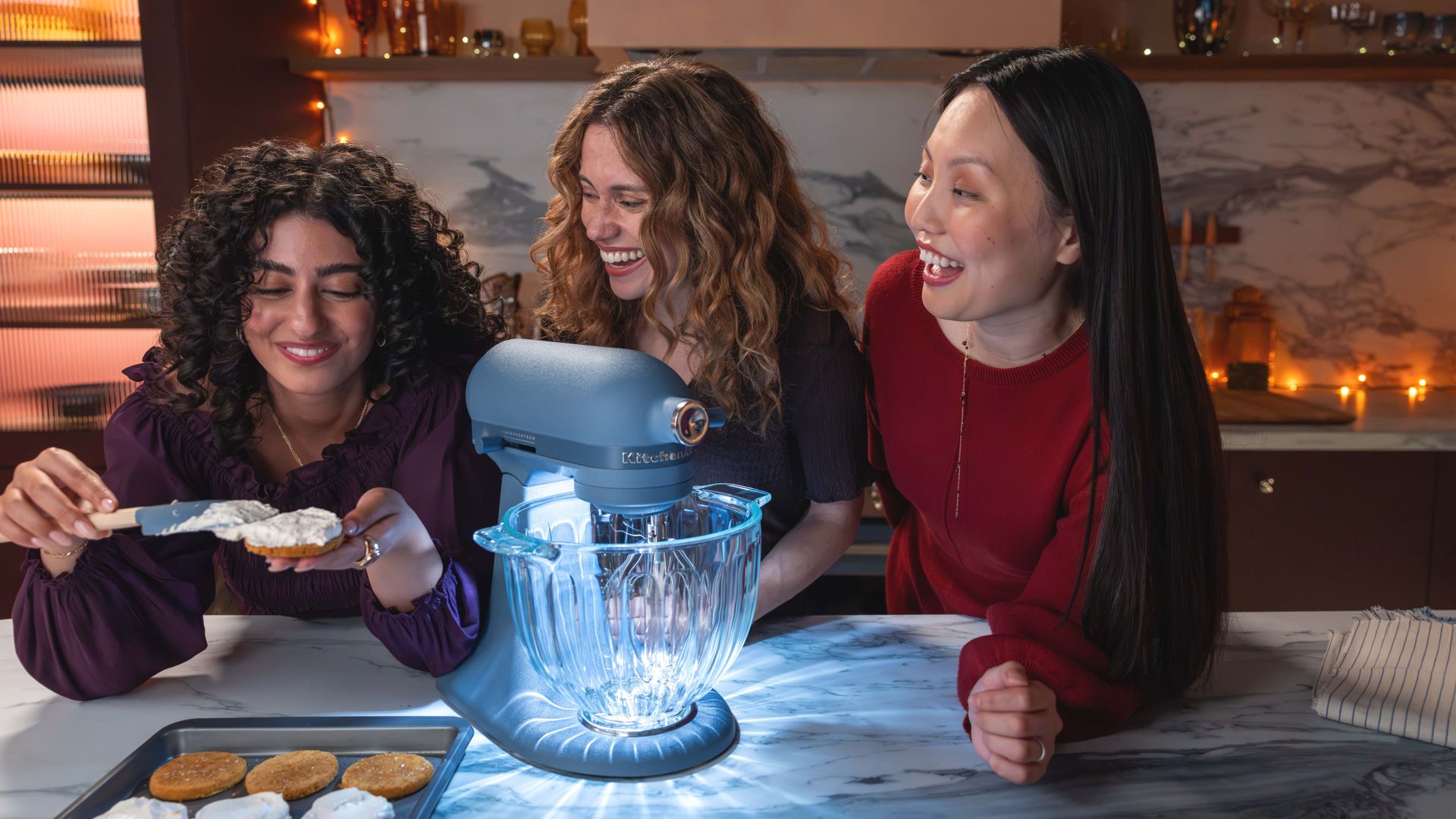 Three women gathered around KitchenAid Luminaire stand mixer