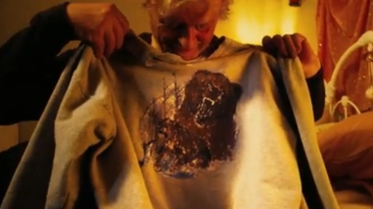 Rutger Hauer holding up a bear sweatshirt in Hobo With a Shotgun