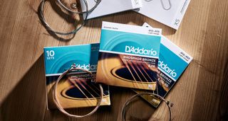 A set of D'Addario guitar strings photographed against a light wood background.