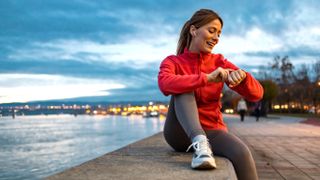 Woman paused during run, using sports watch