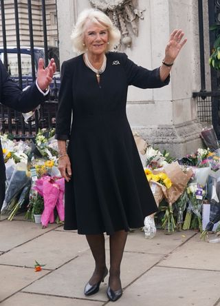 Queen Camilla waving to a crowd