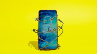 Image of smartphone wrapped in barbed wire. The screen displays a padlock and the phone is in front of a yellow background