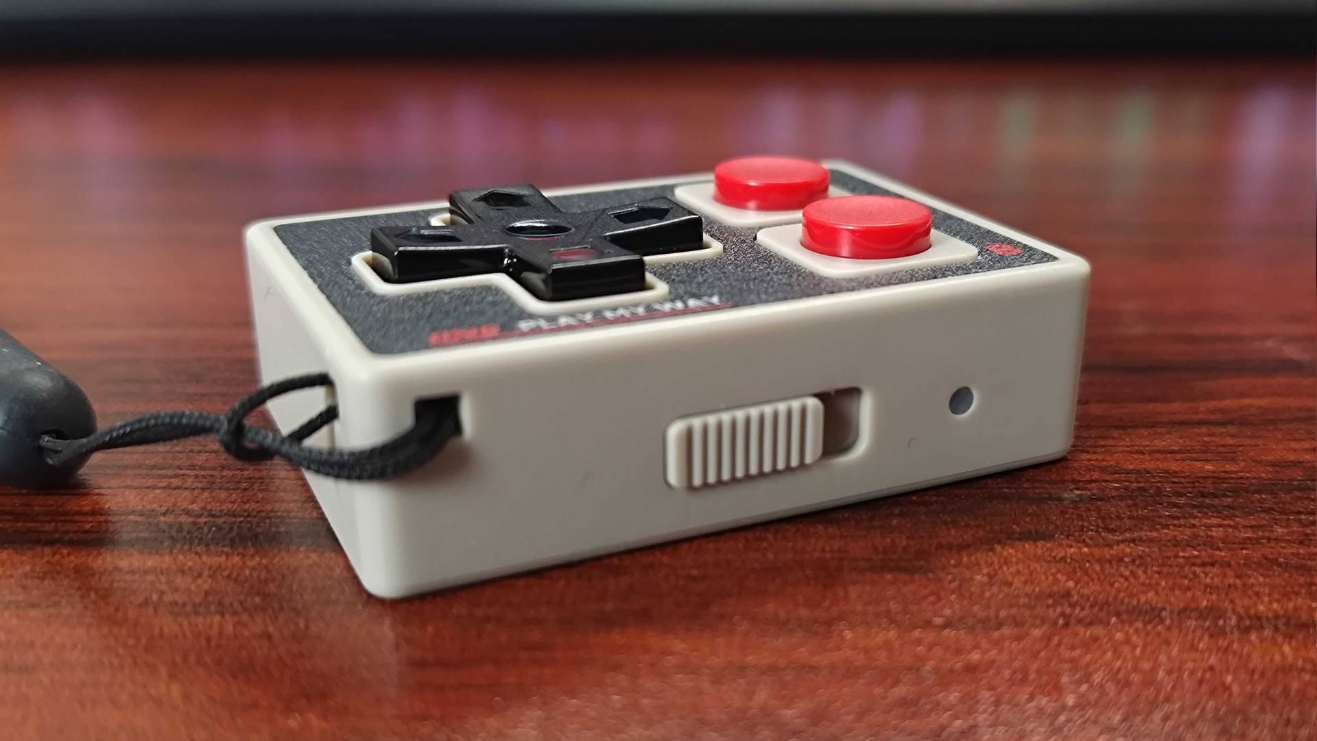 IINE Gamebrick Mini on woodgrain desk with mode switch in view.