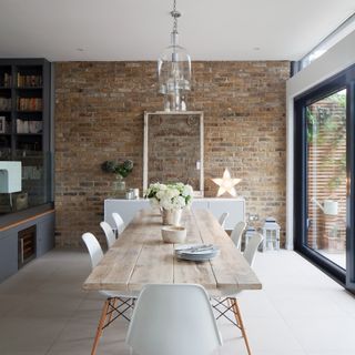 A light and open dining room with a long, rectangular dining table with clear glass pendant lights