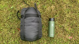 The Rab Solar Eco 3 sleeping bag in its stuff sack with a water bottle for scale