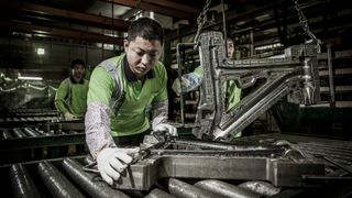 Merida factory employees work with a bike frame mold