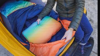 A car camper demonstrating the colorful Rumpl Wrap Sack