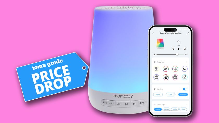 The Momcozy Baby Sound Machine lit up in a pastel blue against a pink background. To the right, a smartphone showing the Momcozy app. To the left, a Tom&#039;s Guide price drop deals badge