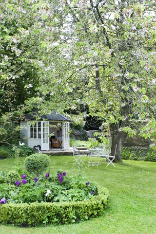 Green lawn with summerhouse and tree in blossom