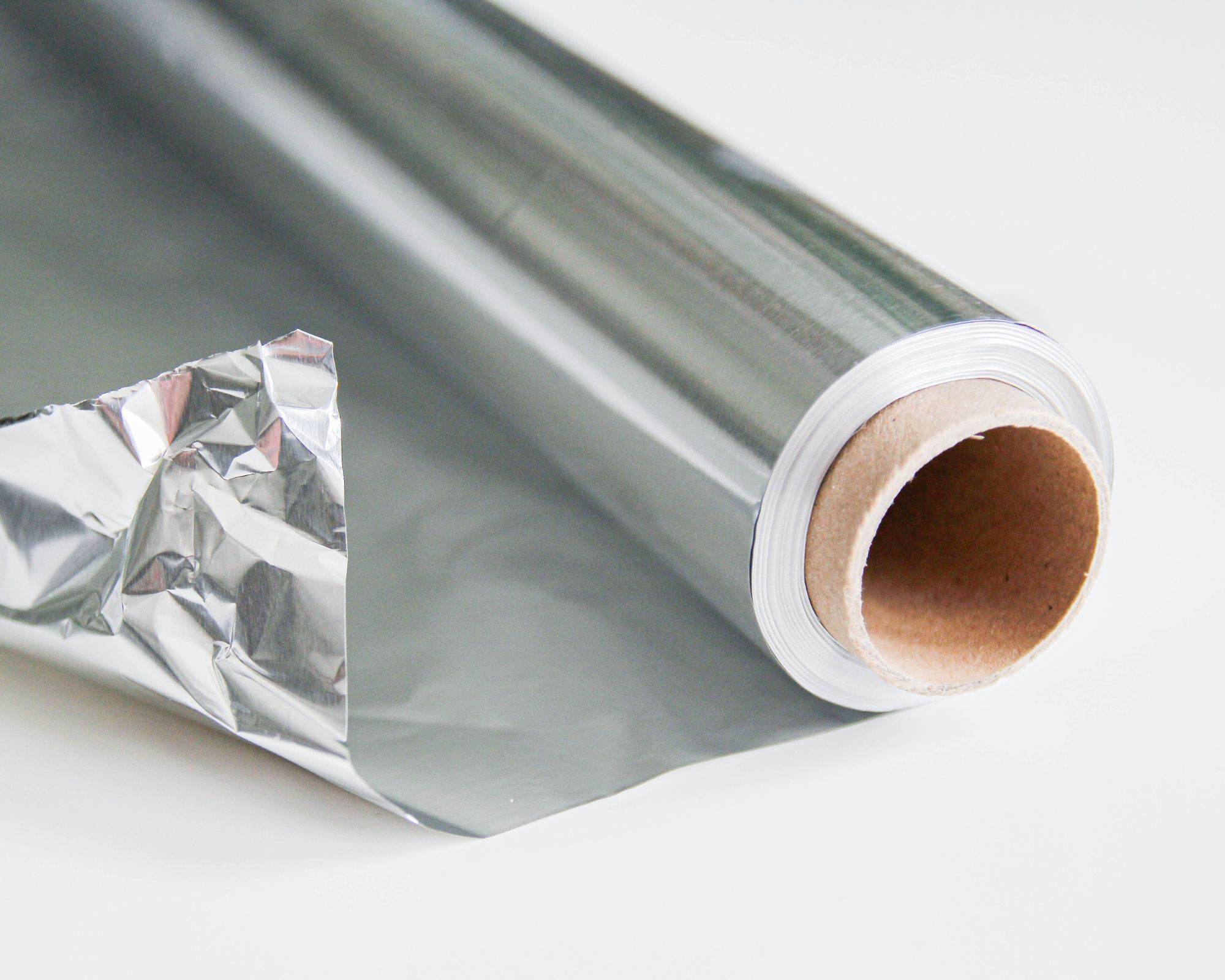Roll of silver aluminium foil wrapped up and on a white background