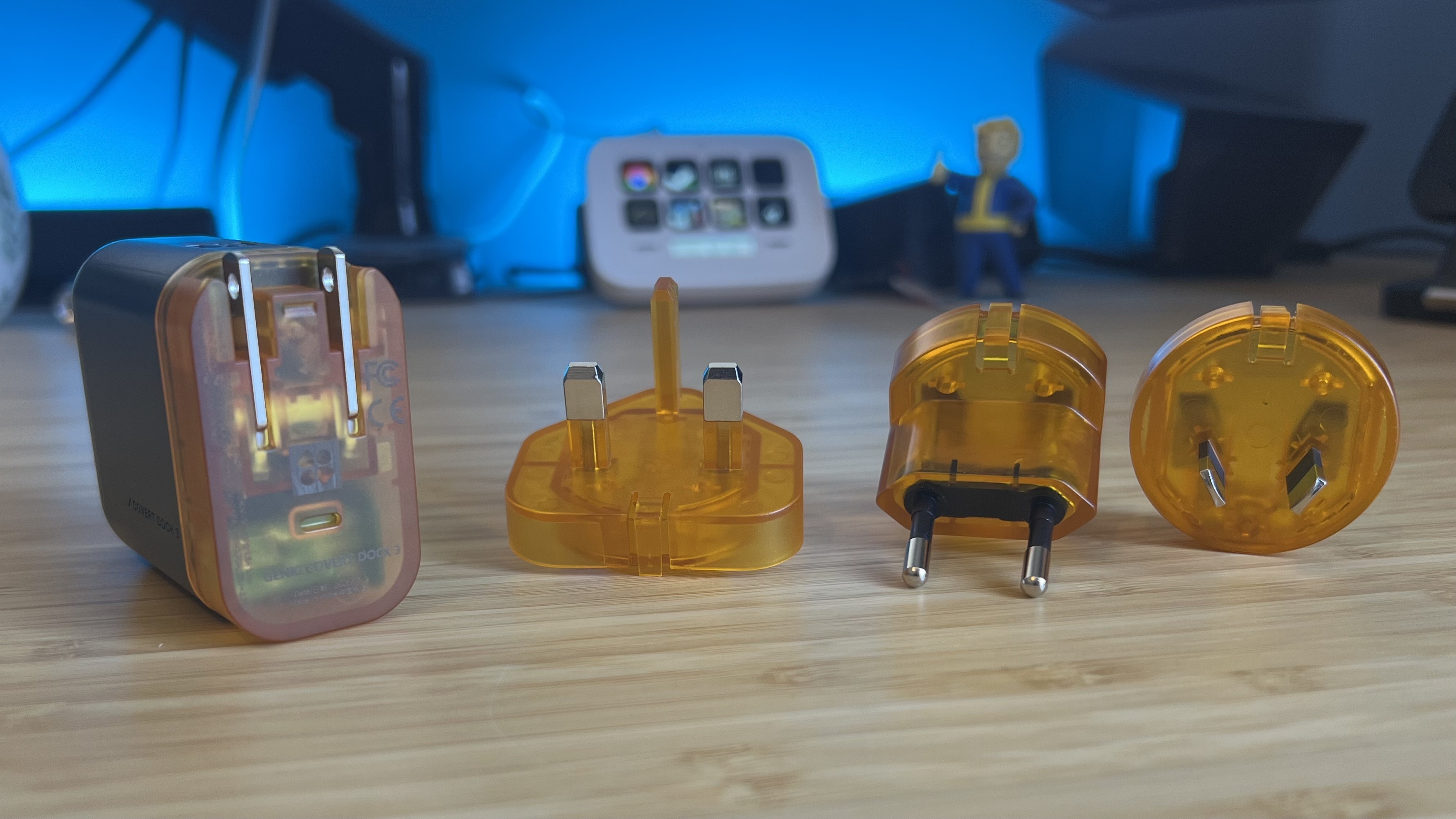 Genki Covert Dock 3 device and international power adapters on a wooden table