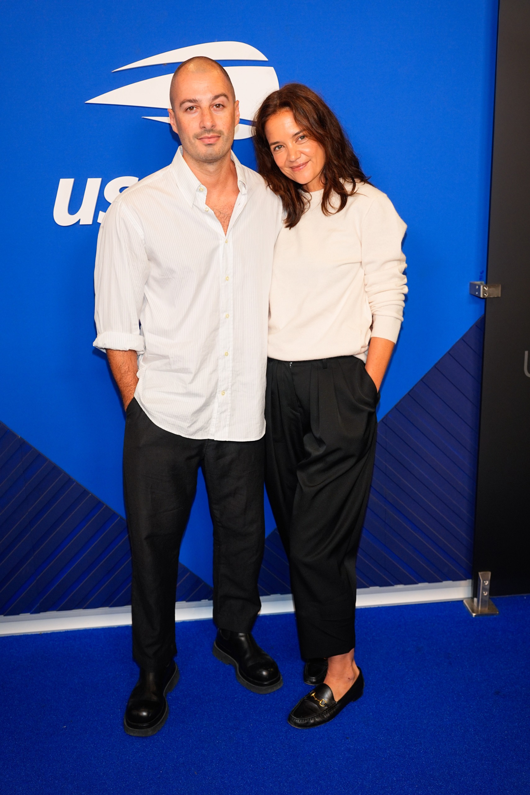 Katie Holmes wore a white crewneck sweater, black trousers, and leather loafers at the 2026 US Open