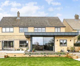 Modern flat roof single storey extension to detached stone-clad house