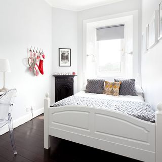 bedroom with white wall and fire place and bedding with cushions and thow