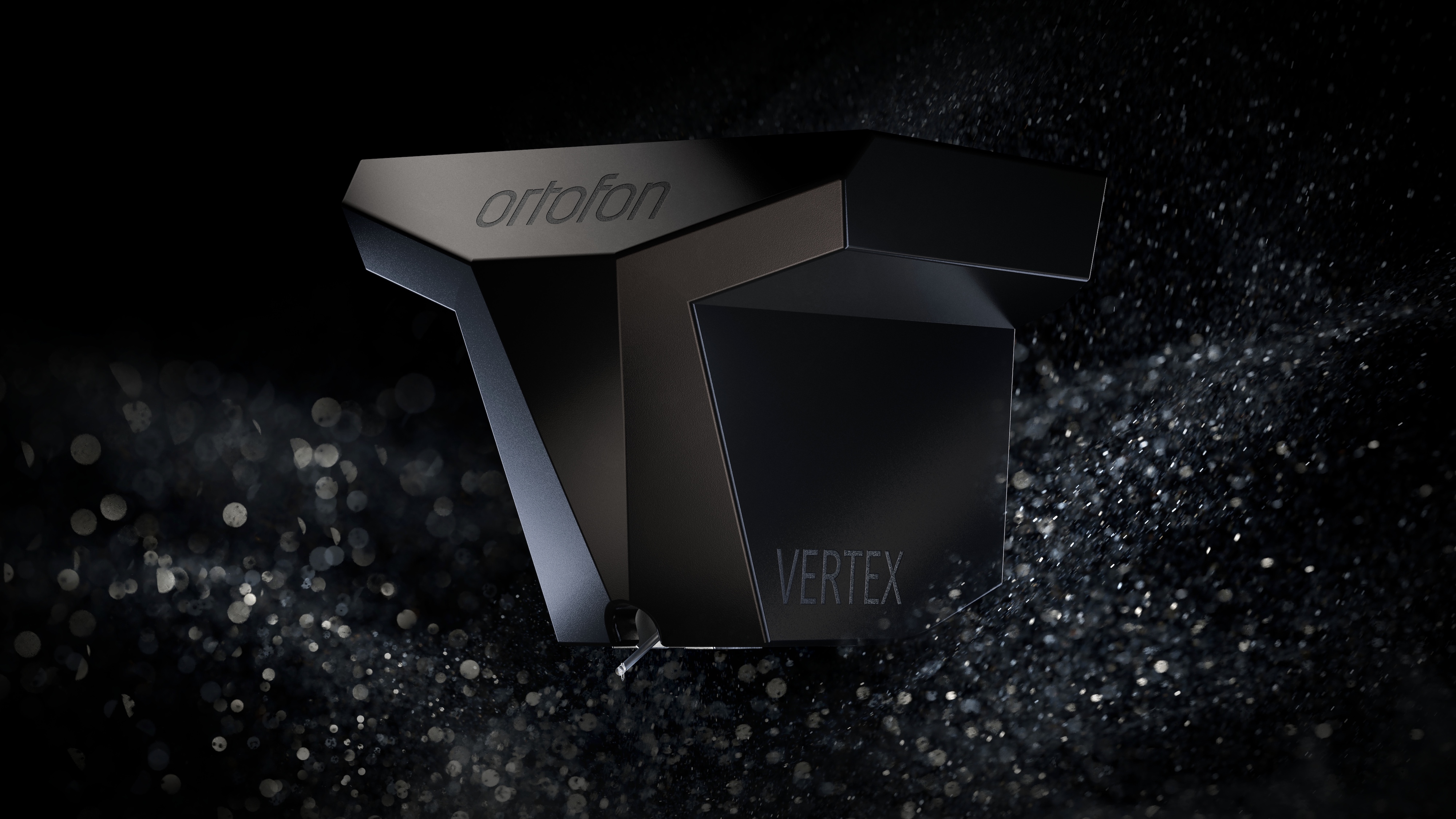 A black Ortofon MC Vertex turntable cartridge on a black background surrounded by water droplets.