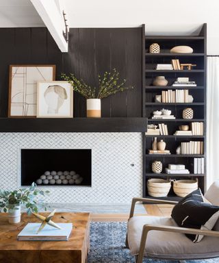 White tiled fireplace hearth flush to black paneled wall with decorative accents on mantel and bookshelf