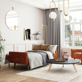 A single sofa bed in orange velvet extended in a modern living room with brass ceiling light fixture