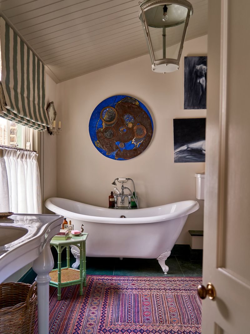 Bathroom with an antique-style clawfoot tub, purple patterned rug, and green bamboo side table