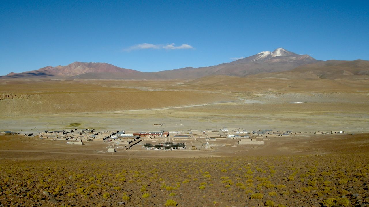 a wide view of a small town with volcanoes in the background