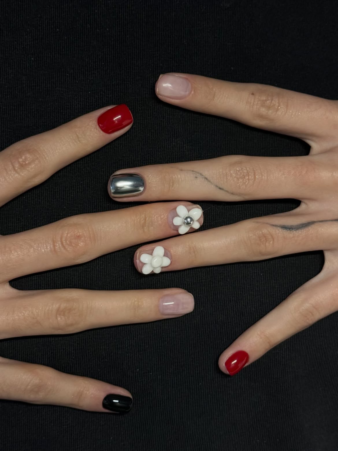 Mismatched manicure with red, black, chrome, and 3D white flowers