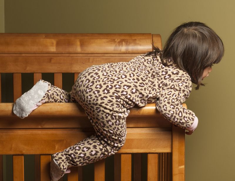 A toddler climbs out of her crib.