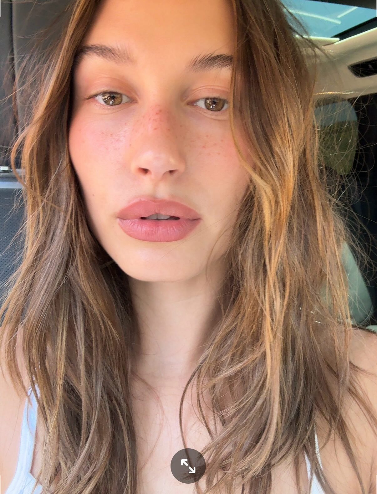Hailey Bieber prend un selfie avec des cheveux brillants et ébouriffés
