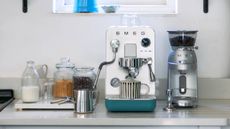 Lifestyle image of the The Smeg MiniPro Coffee Machine and Smeg Espresso Coffee Grinder sitting on a kitchen counter