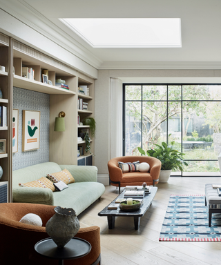 sitting area with sofa and armchair and coffee table and crittal walls and bookshelves and rug