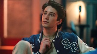 Milo Manheim holding a necklace in School Spirits. 