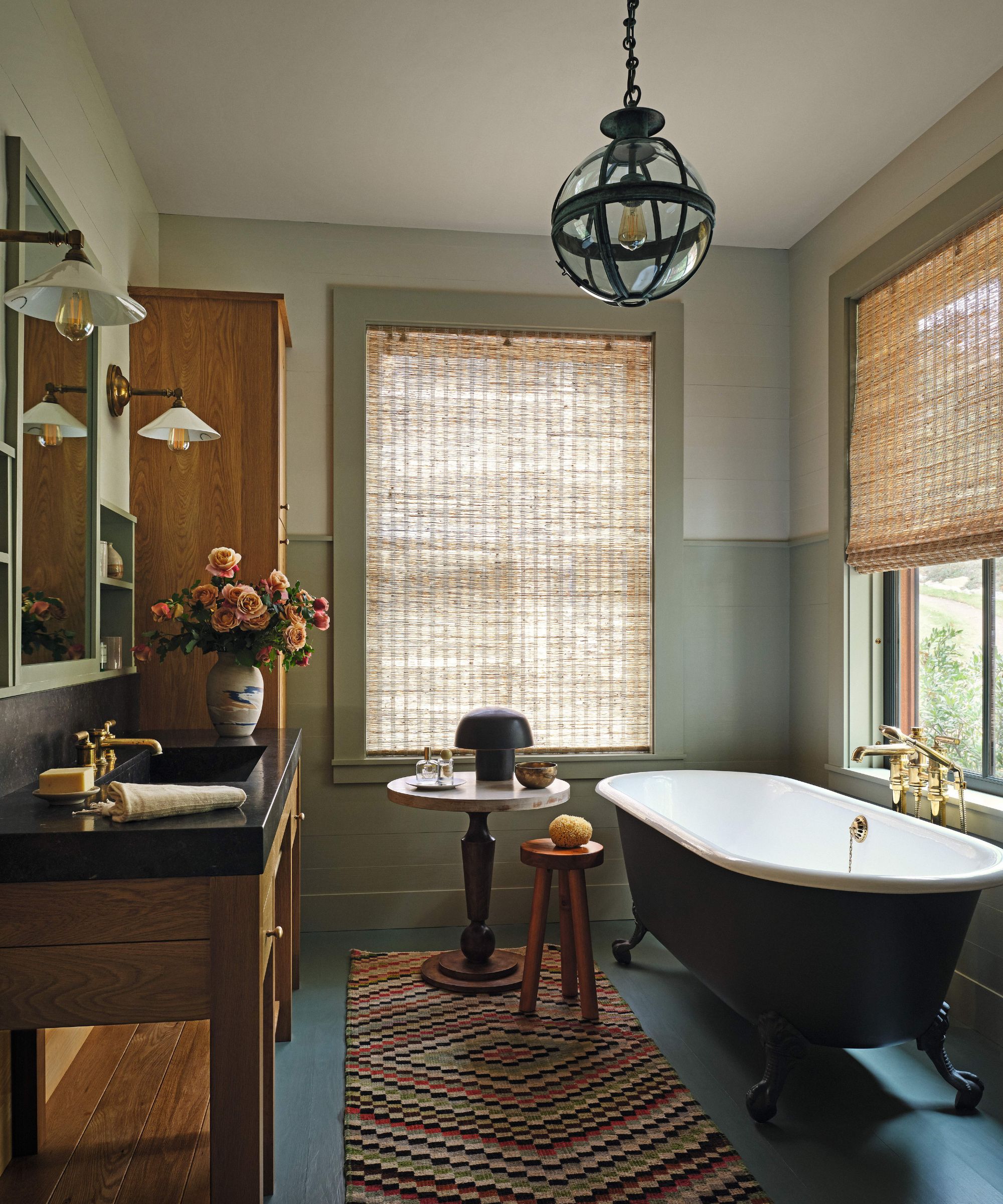 Bathroom with pale green and white wall and blue painted floor boards and dark freestanding bath