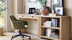 Light wooden desk with green office chair, with books and laptop