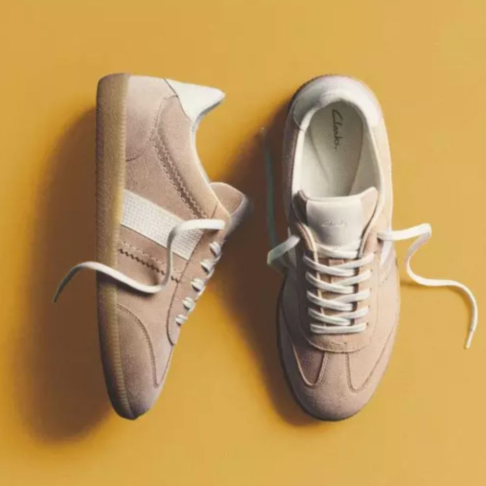 Beige Clarks trainers on yellow square background