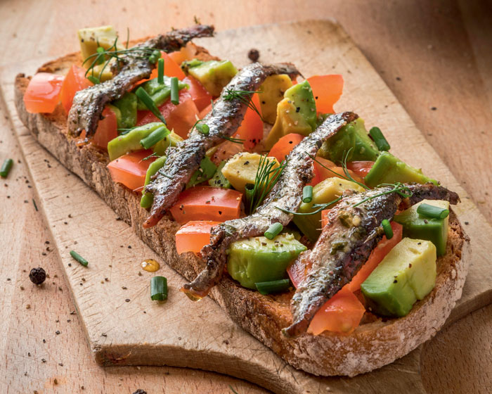 Toasted sourdough bread with avocado, tomato and anchovies