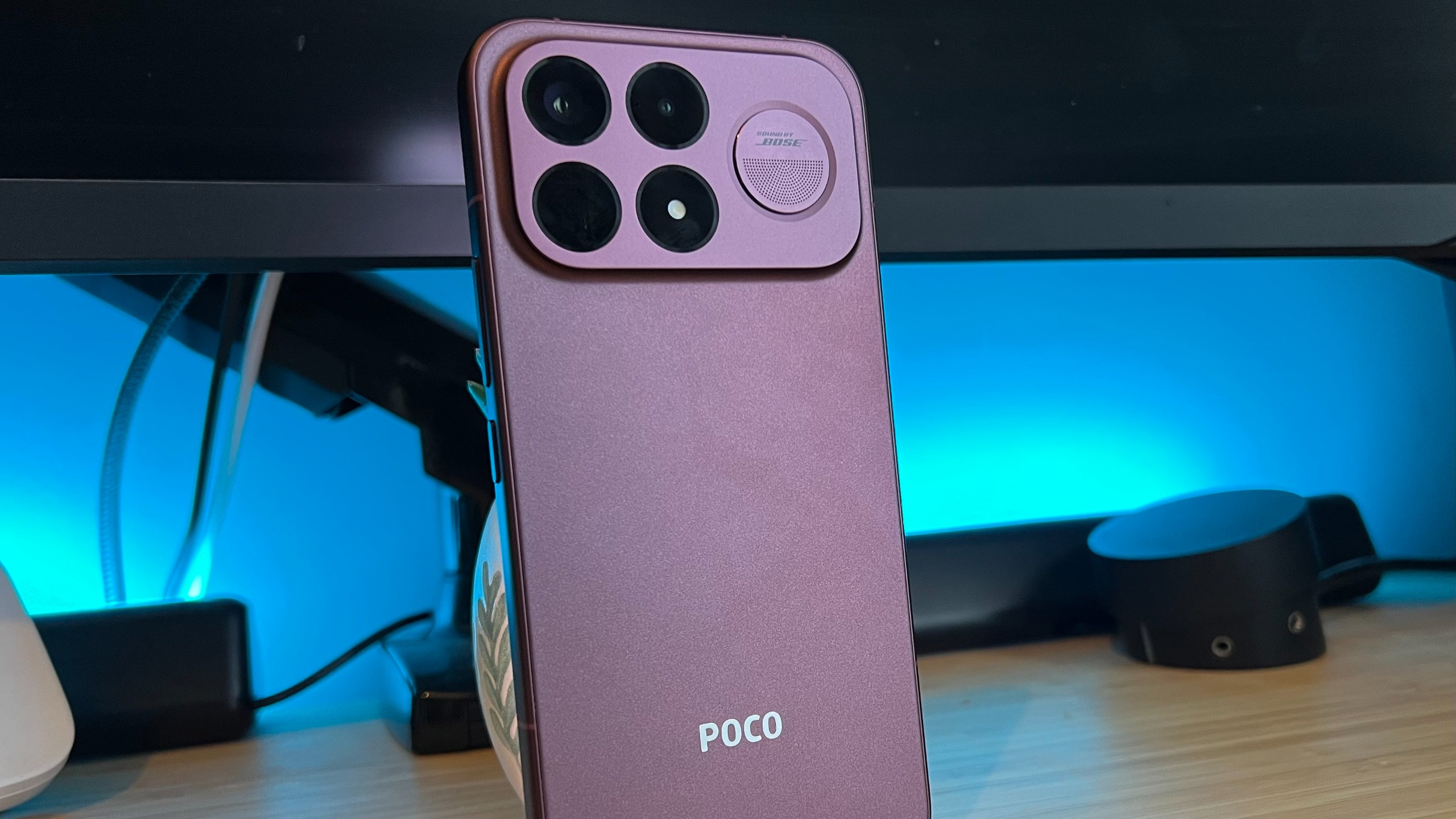 Poco F9 Ultra smartphone standing upright on a wooden desk with blue backlighting