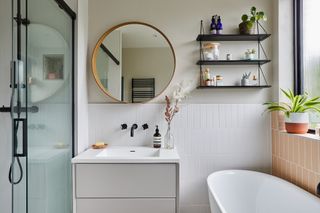 Bathroom with white and pink vertical metro tiles, round mirror and matt black hardware